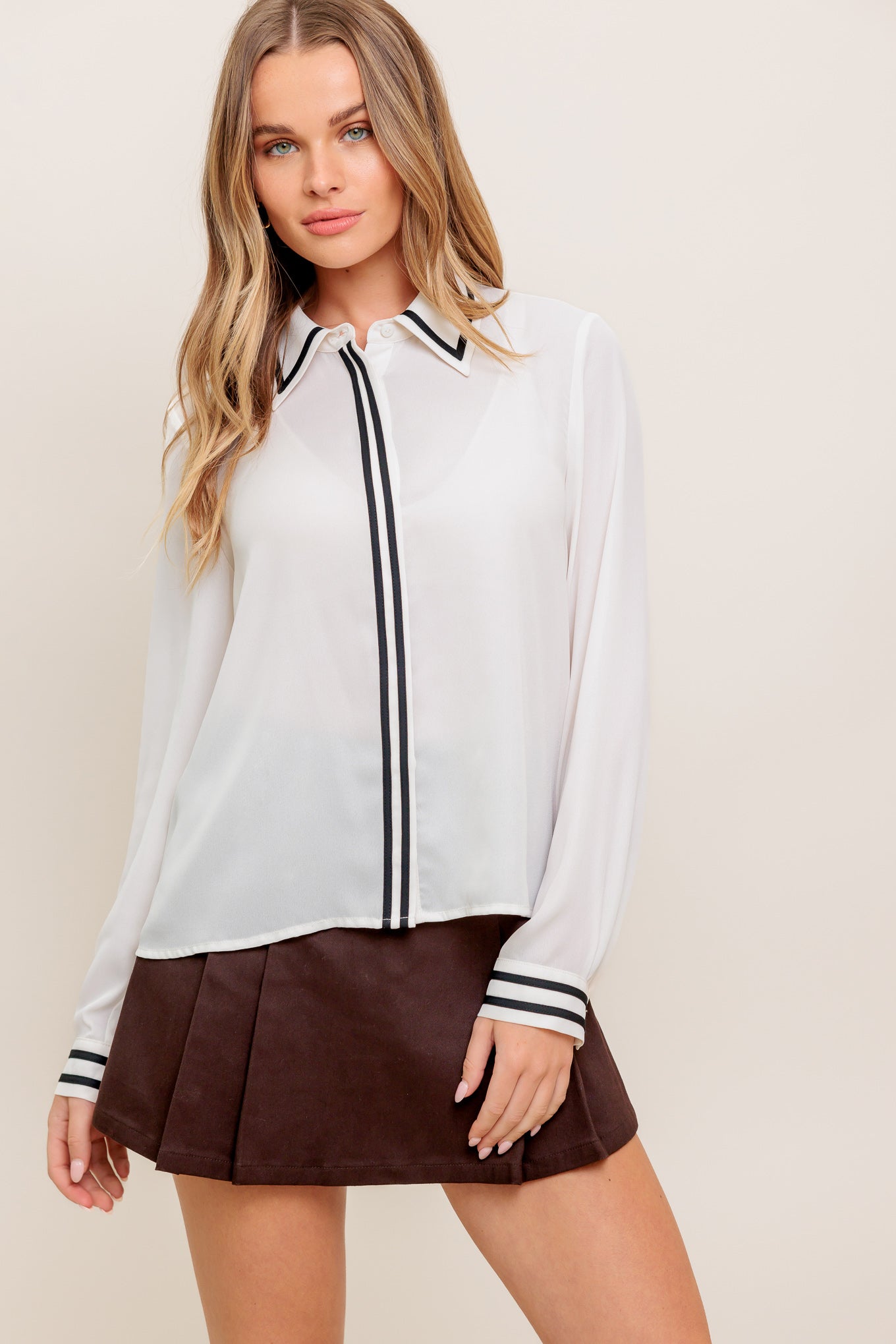 A solid woven top featuring collar, hidden button down and long sleeve