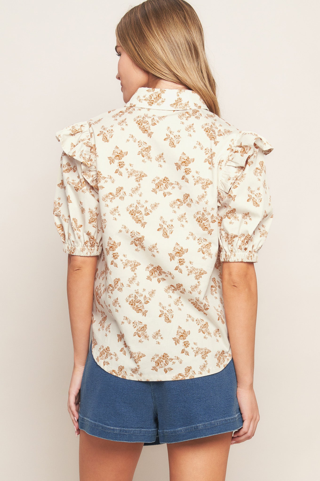 A printed woven top featuring collar, snap button down, ruffled shoulder, short puff sleeve and pockets