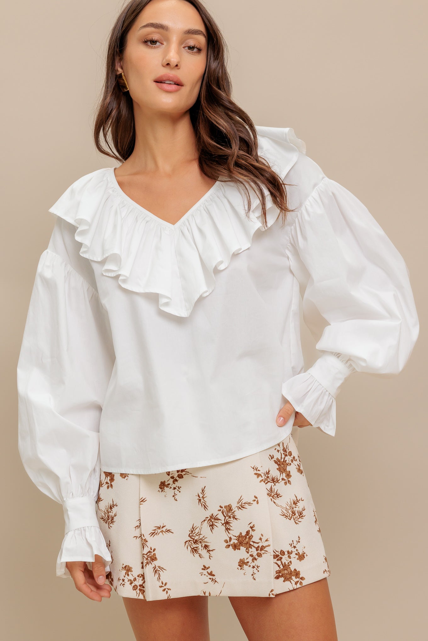 A solid woven top featuring V neckline with ruffles and long puff sleeve with cuff