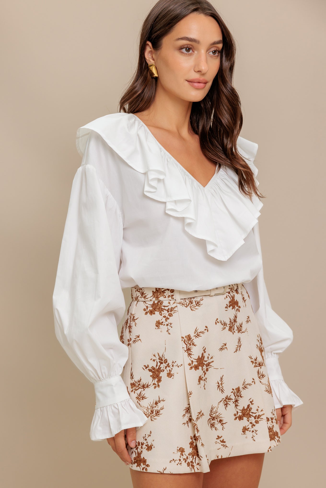 A solid woven top featuring V neckline with ruffles and long puff sleeve with cuff