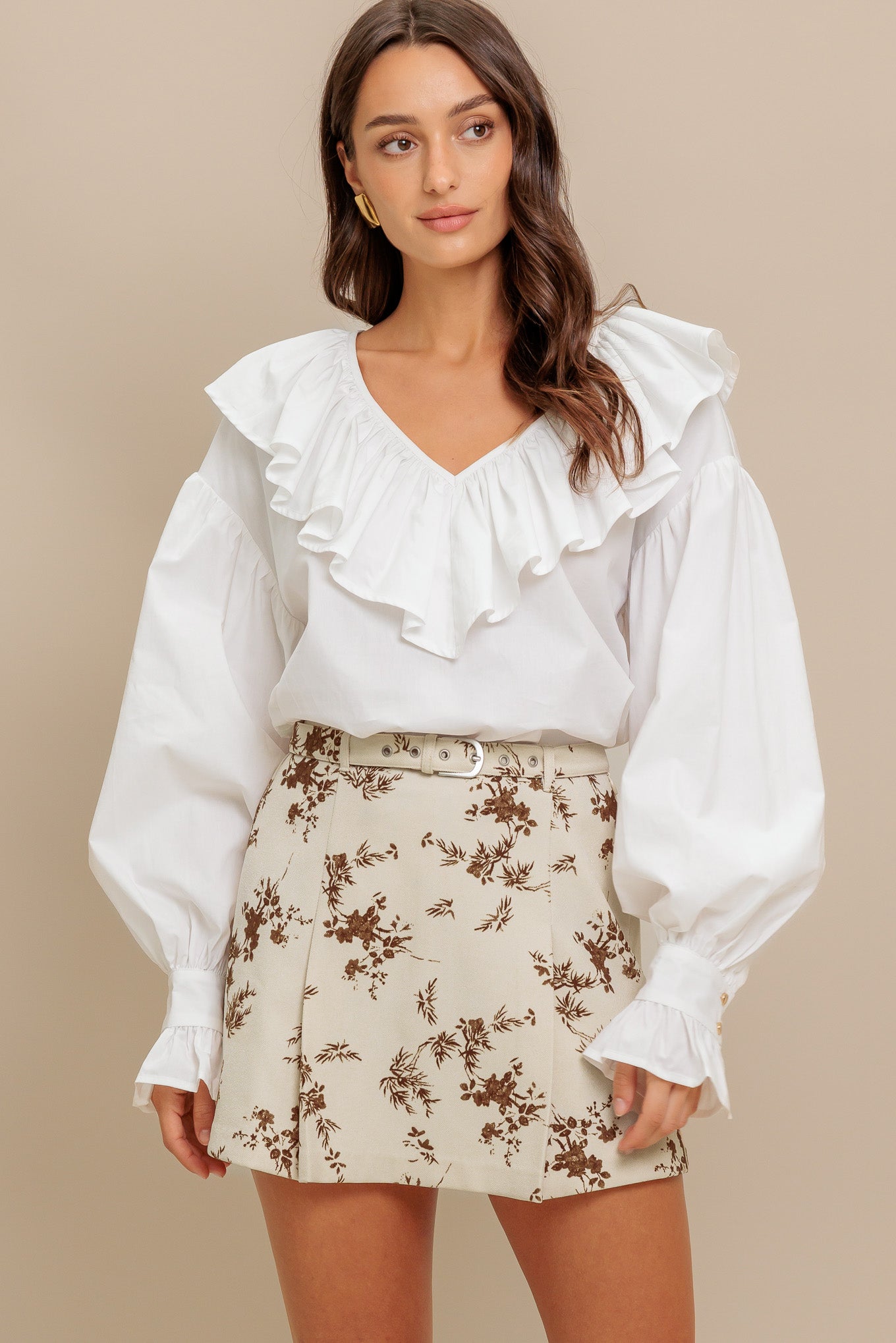 A solid woven top featuring V neckline with ruffles and long puff sleeve with cuff