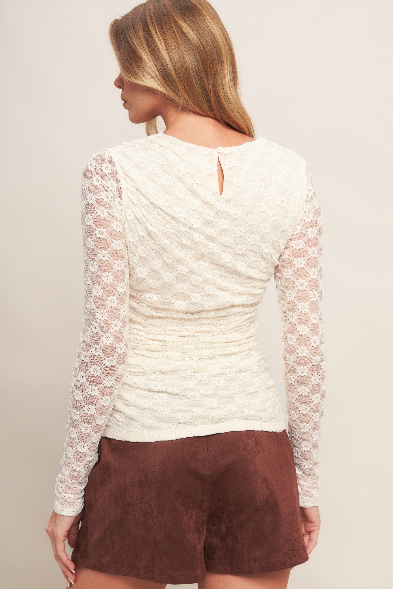 A stretch knit lace top with long sleeve and back neck button closure