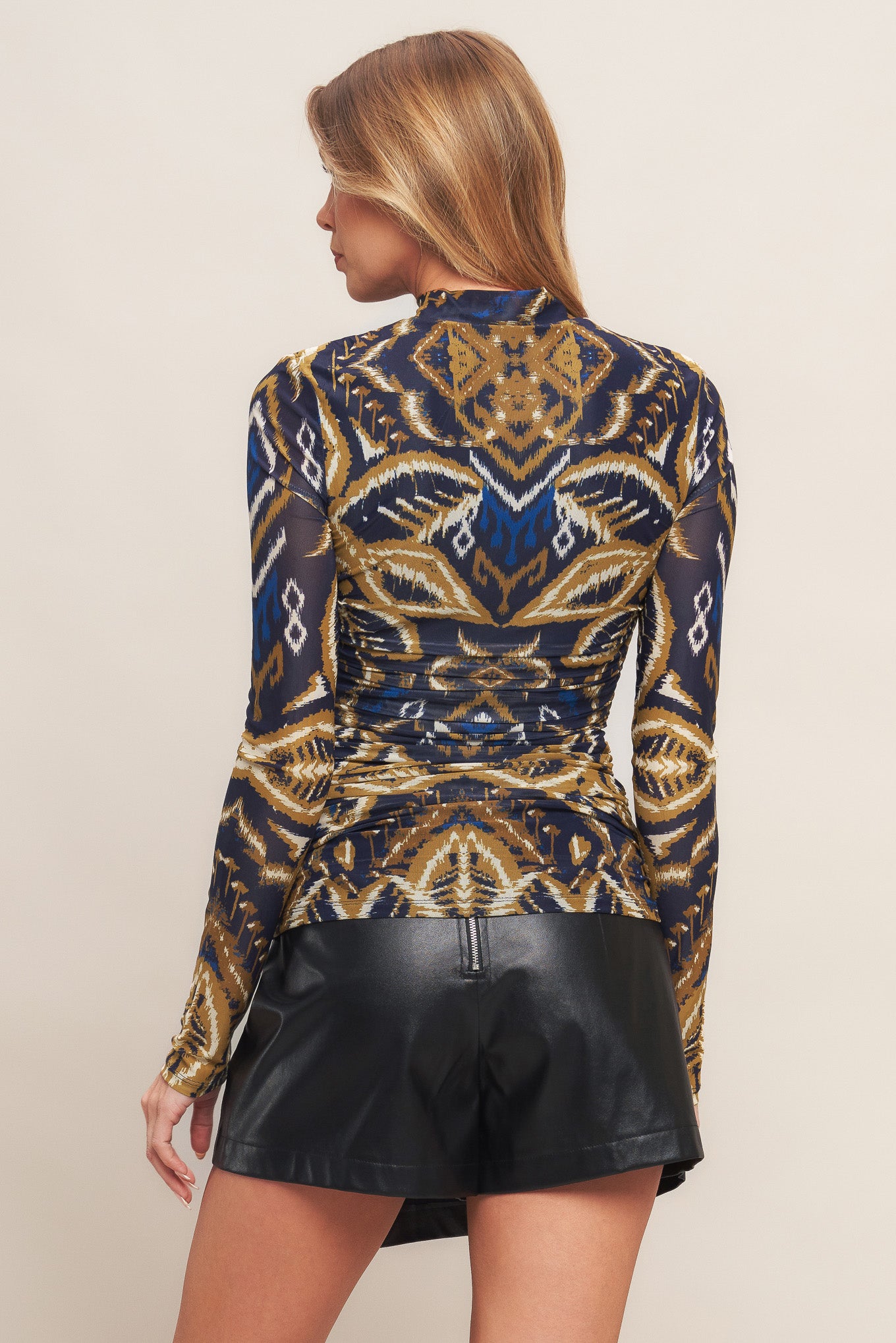 A printed power mesh top with high neckline and long sleeve with side shirring.