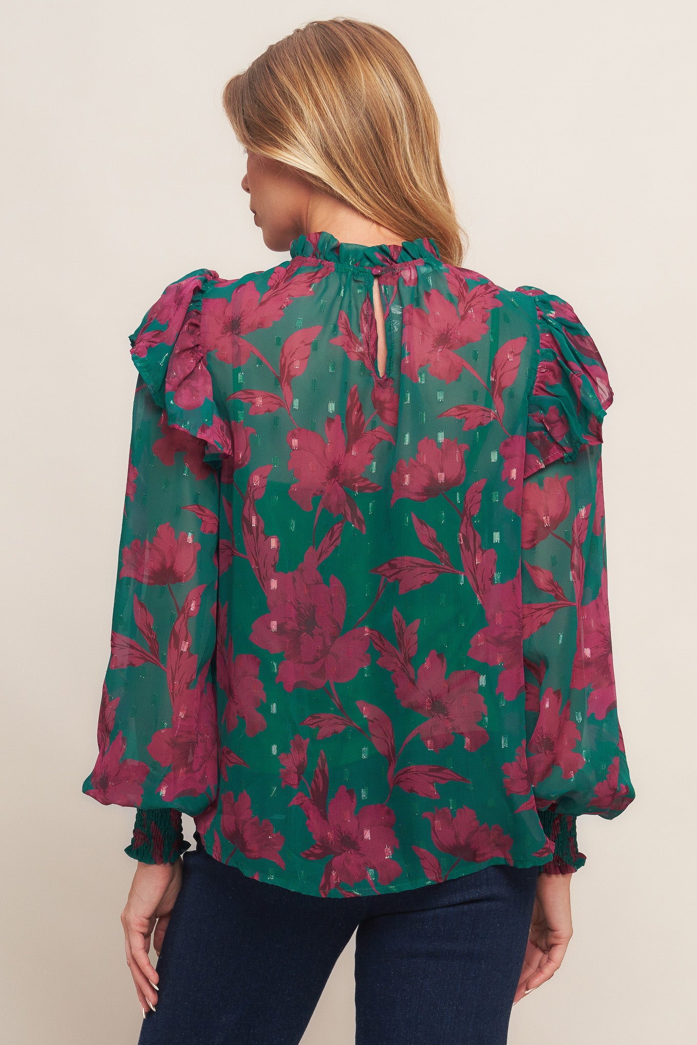 A printed woven top featuring high ruffled neckline, long sleeve with ruffed shoulder, back neck button closure and cami