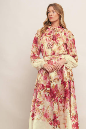 A printed woven top featuring ruffled neckline with front tie and long sleeve with smocked cuff