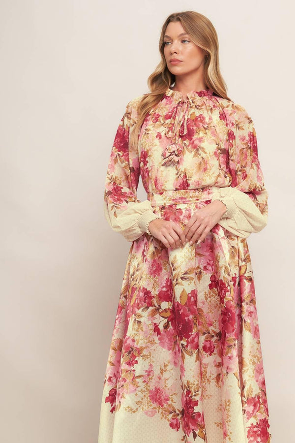 A printed woven top featuring ruffled neckline with front tie and long sleeve with smocked cuff