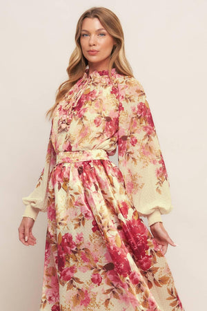 A printed woven top featuring ruffled neckline with front tie and long sleeve with smocked cuff