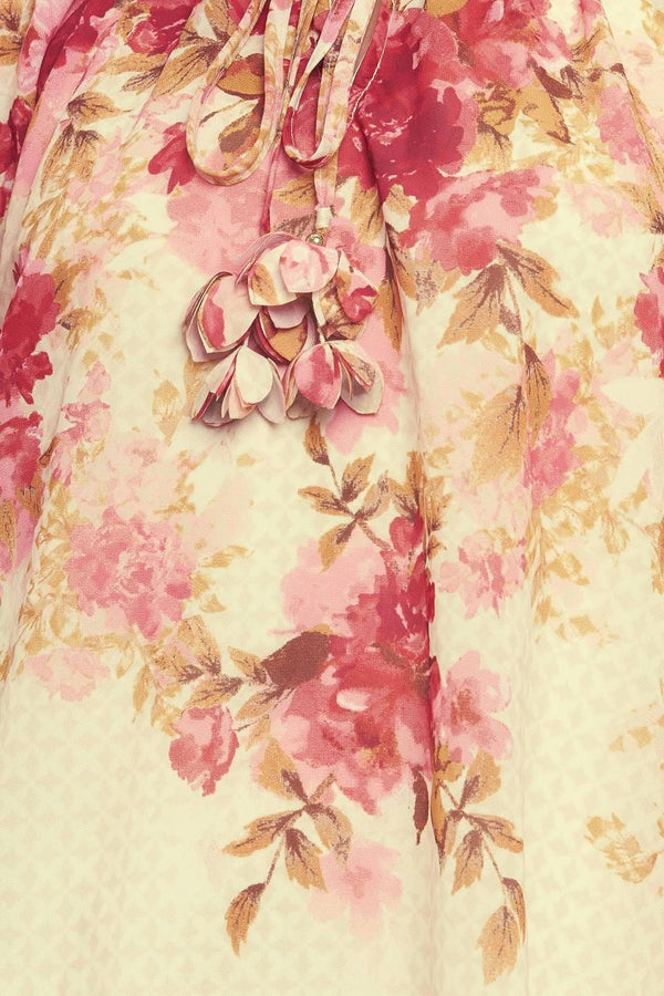 A printed woven top featuring ruffled neckline with front tie and long sleeve with smocked cuff