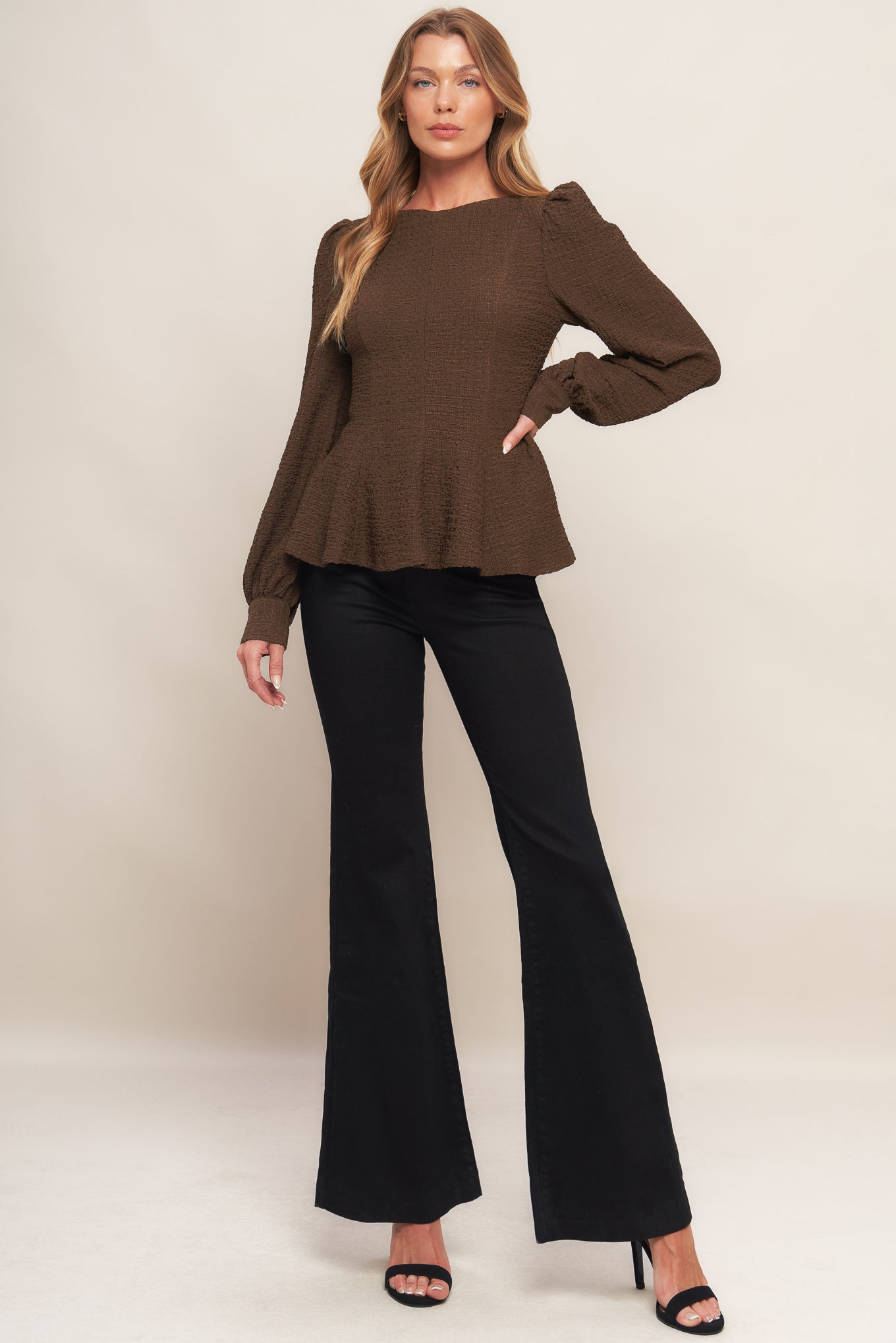 A textured woven top featuring round neckline, long sleeve, peplum and back zipper closure