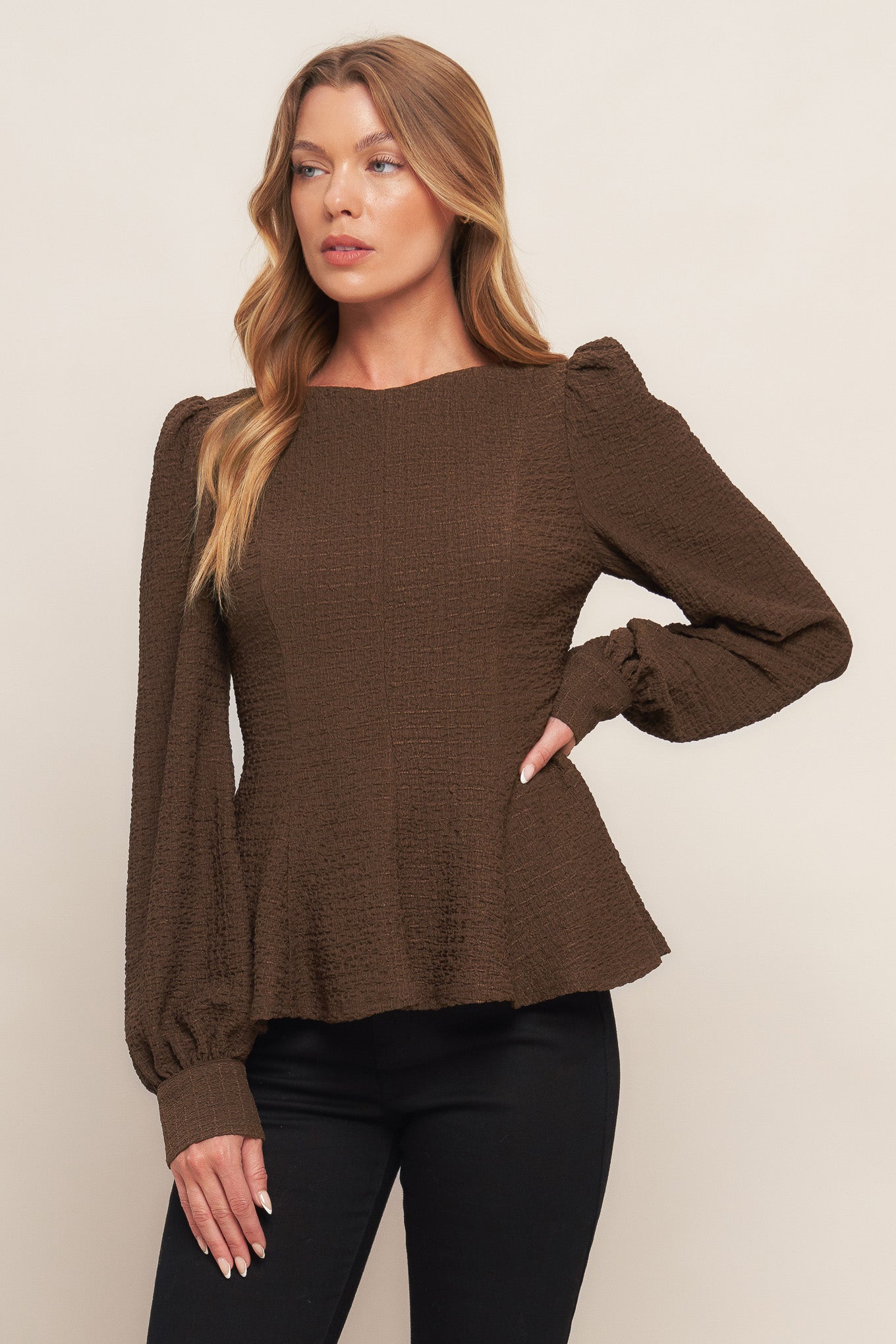 A textured woven top featuring round neckline, long sleeve, peplum and back zipper closure