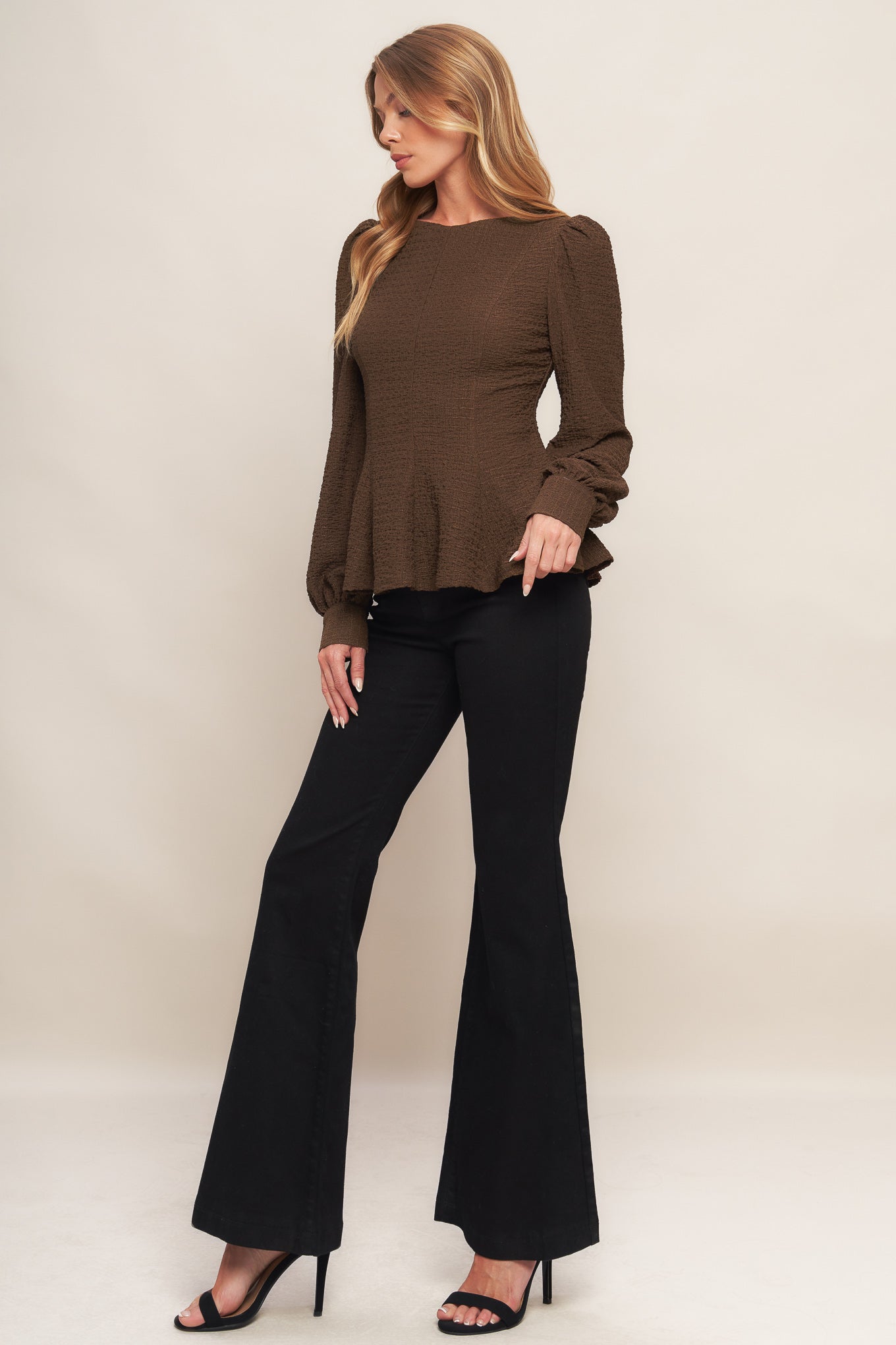 A textured woven top featuring round neckline, long sleeve, peplum and back zipper closure