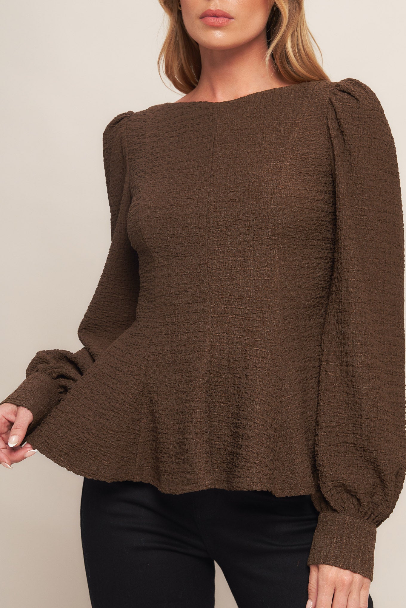 A textured woven top featuring round neckline, long sleeve, peplum and back zipper closure