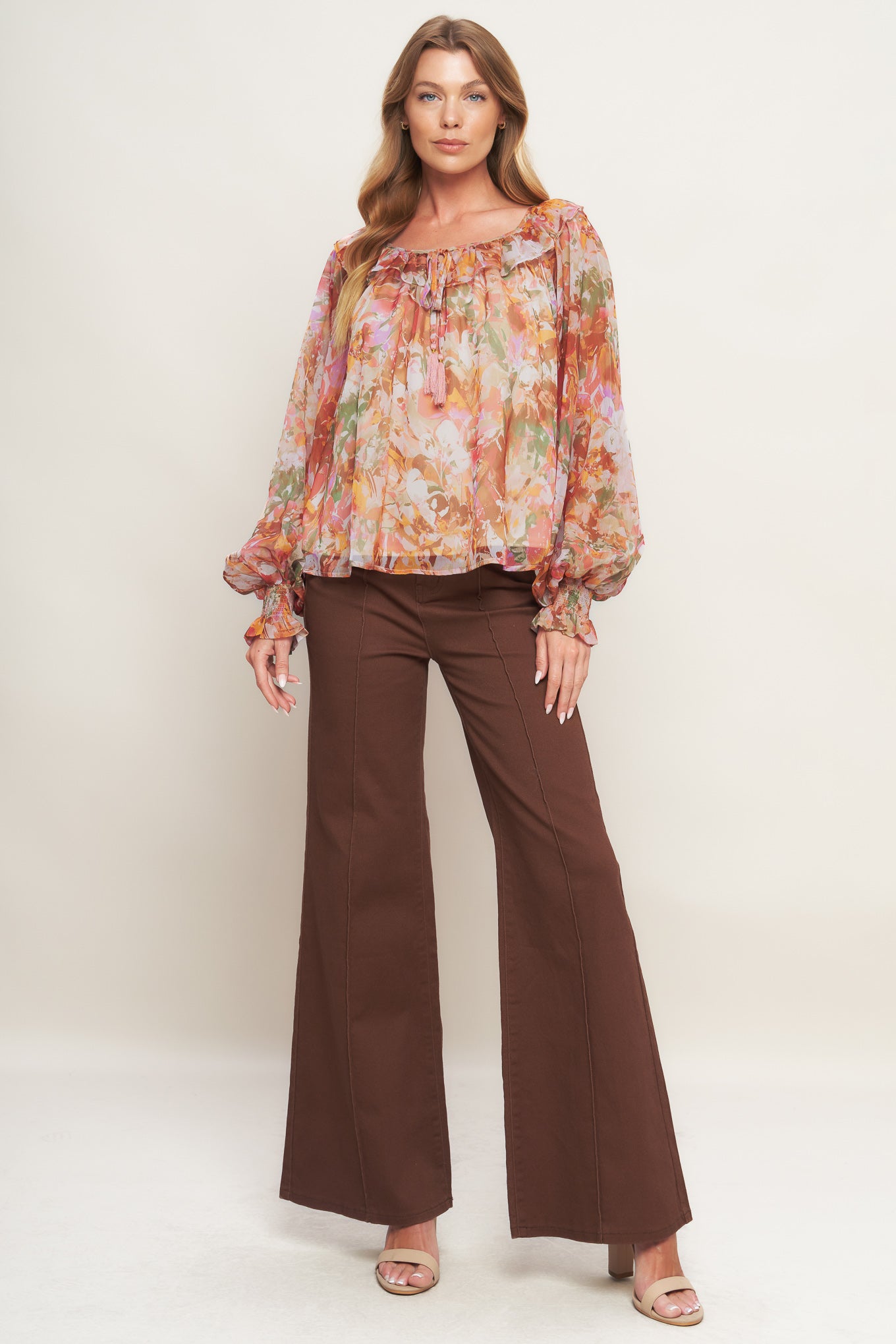 A printed woven top featuring wide round neckline with ruffles, front tie and tassel, long blouson sleeve with ruffled cuff and lining