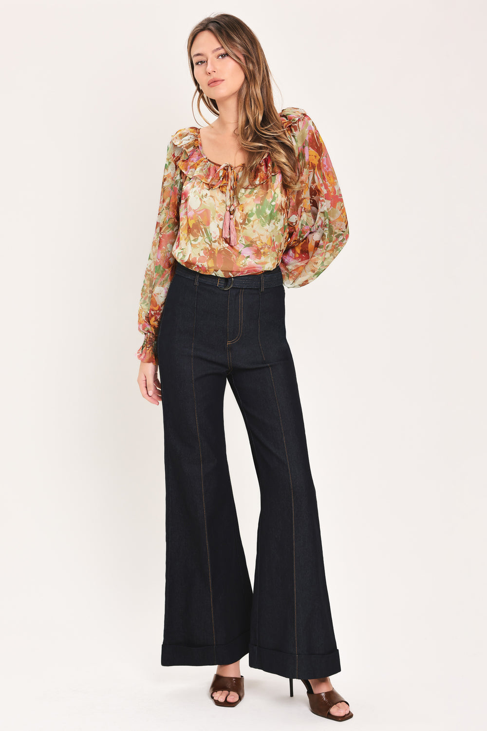 Woman wearing a long sleeve, u-neckline floral rust multicolor blouse with small bow detail and tassels on the center chest | Flying Tomato