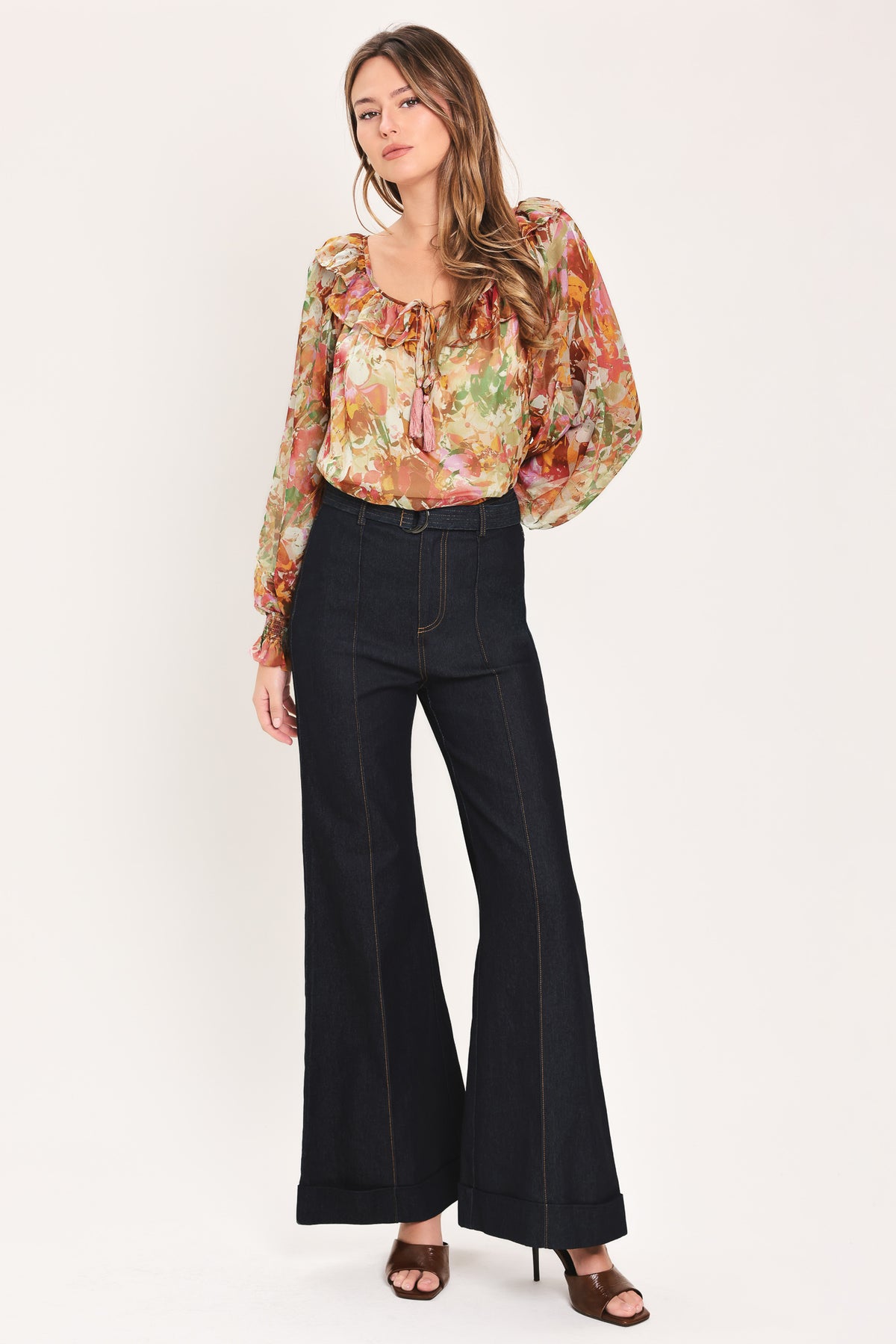 Woman wearing a long sleeve, u-neckline floral rust multicolor blouse with small bow detail and tassels on the center chest | Flying Tomato