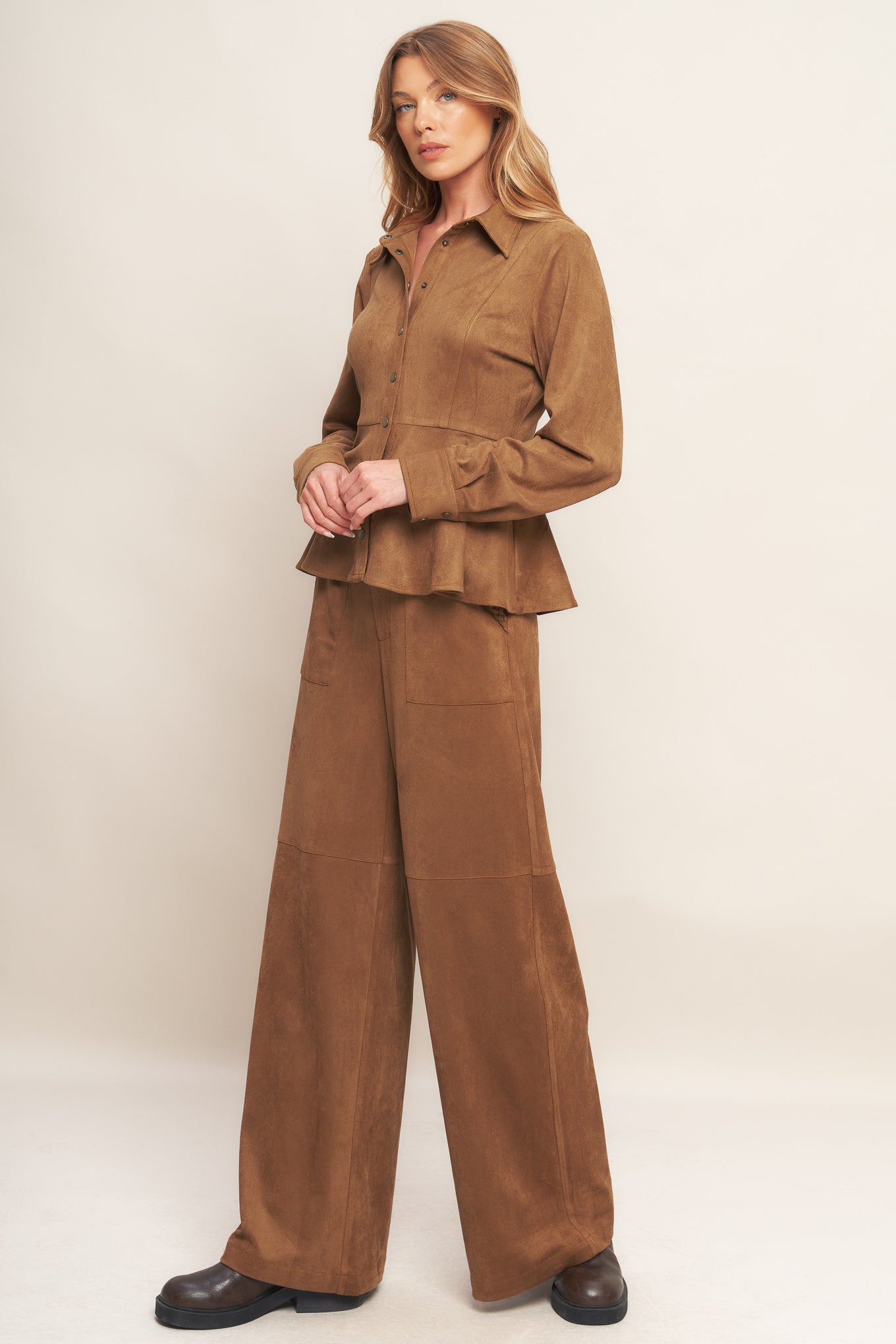 A faux suede top featuring collar, long sleeve, front button down and peplum.