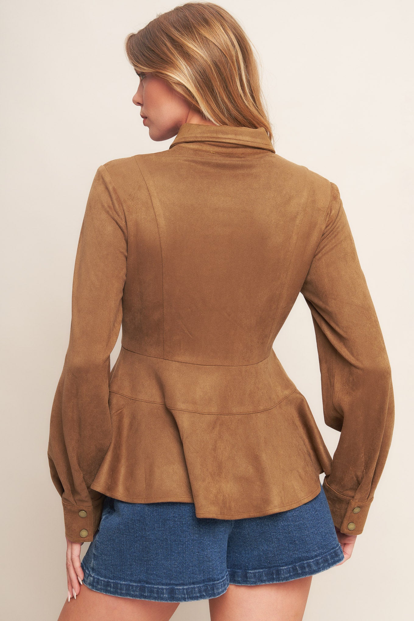 A faux suede top featuring collar, long sleeve, front button down and peplum.