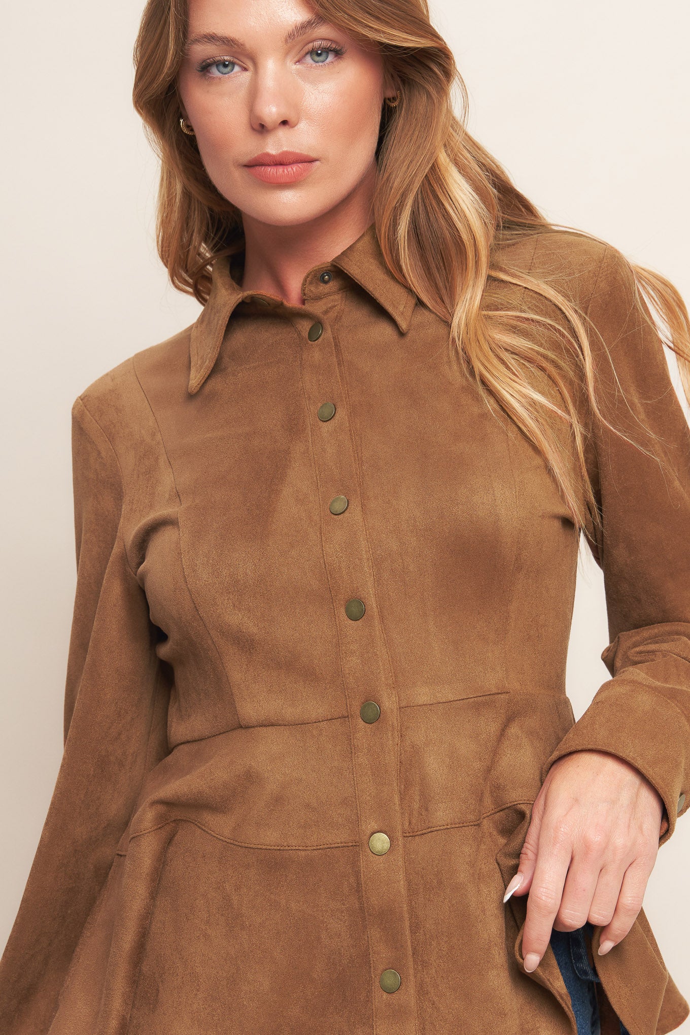 A faux suede top featuring collar, long sleeve, front button down and peplum.