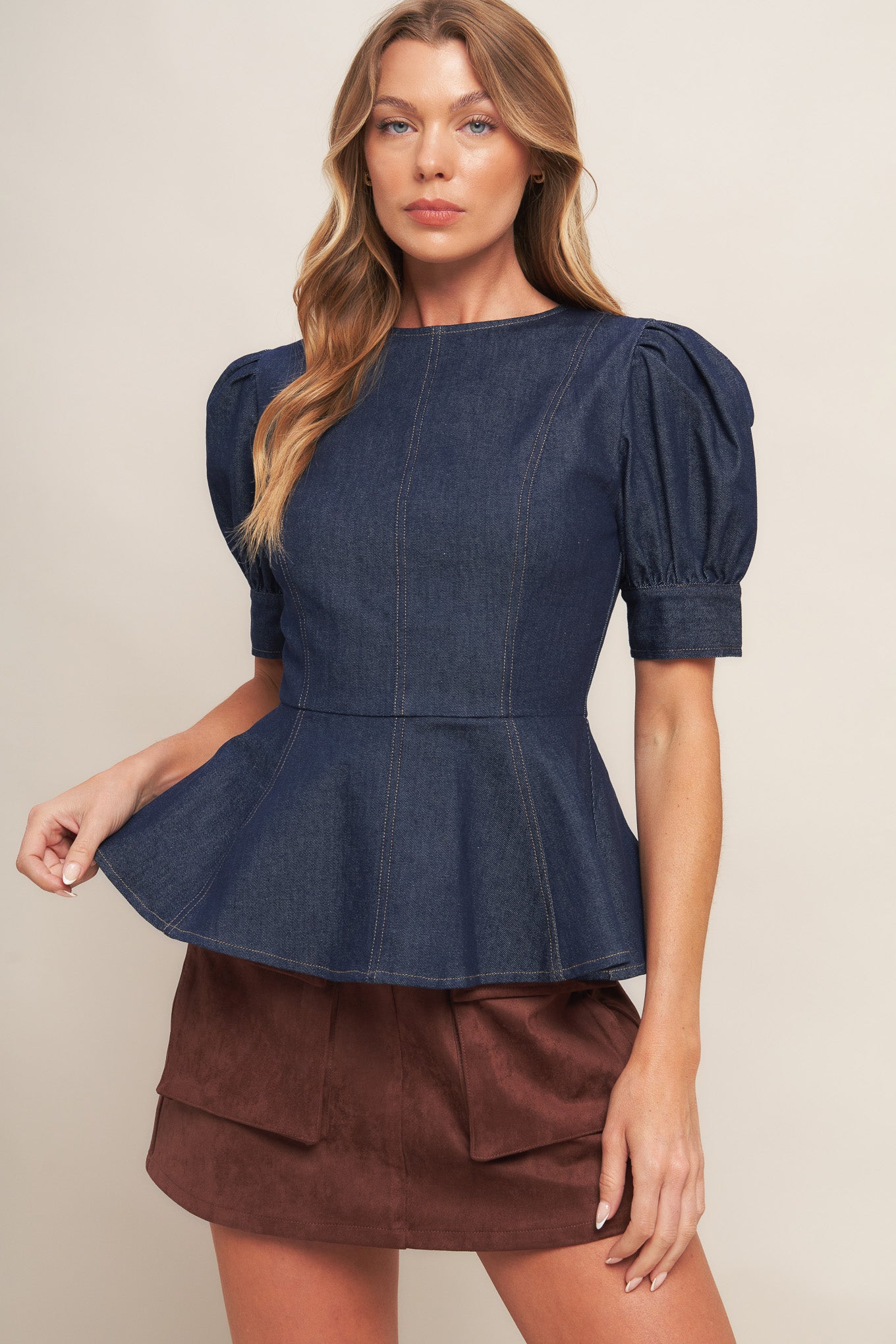 A denim top featuring round neckline, short puff sleeve with cuff, peplum and back zipper closure
