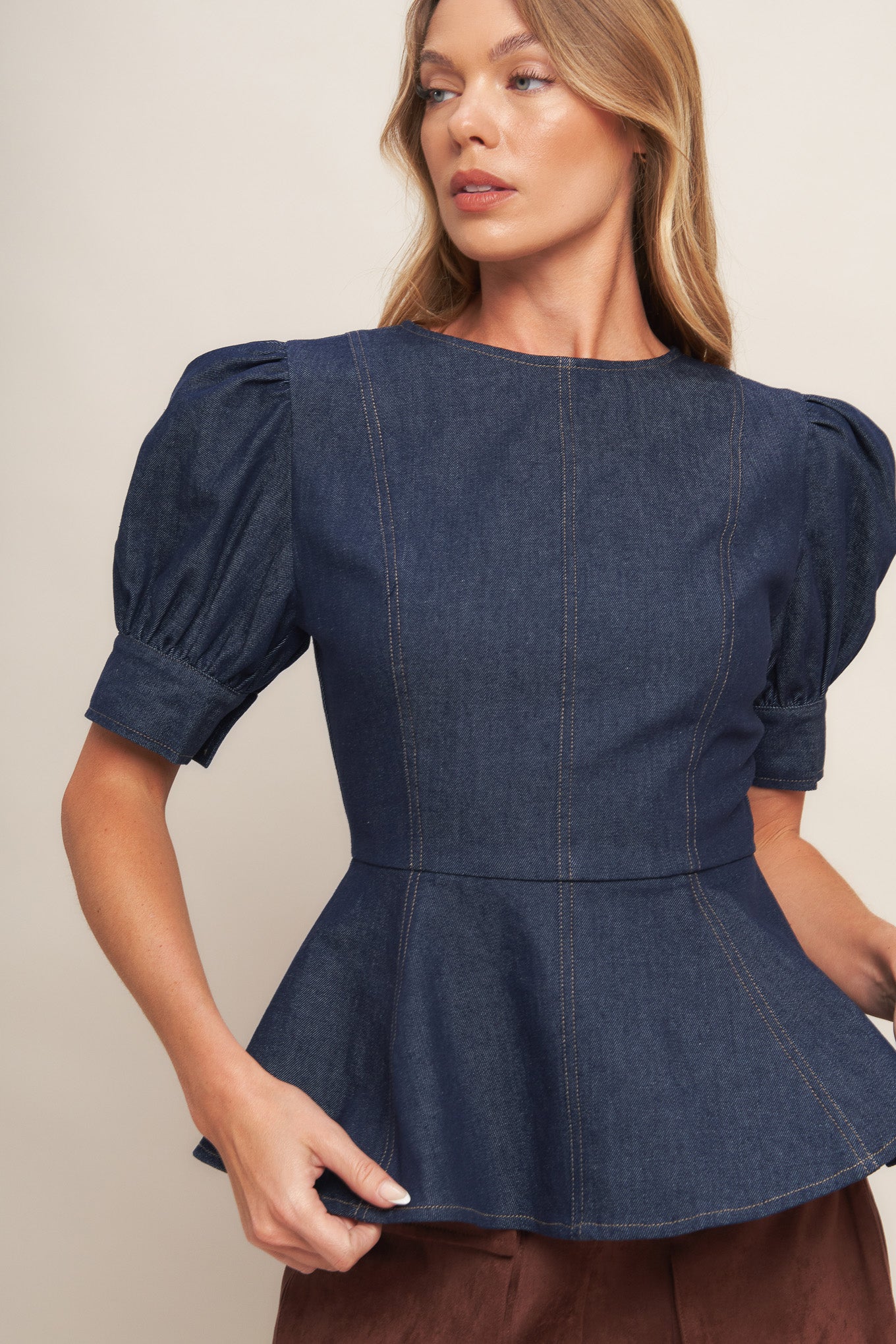 A denim top featuring round neckline, short puff sleeve with cuff, peplum and back zipper closure