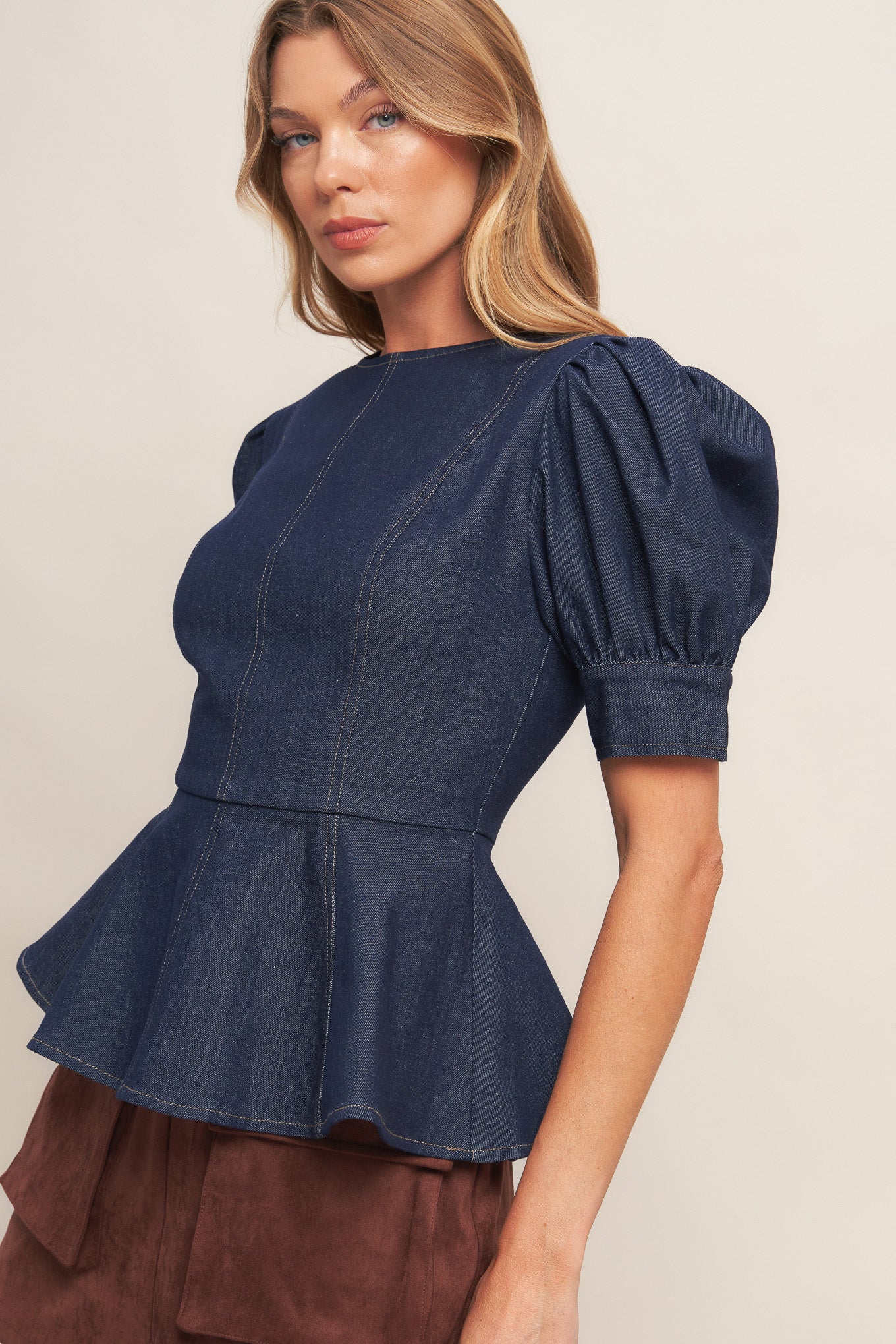 A denim top featuring round neckline, short puff sleeve with cuff, peplum and back zipper closure