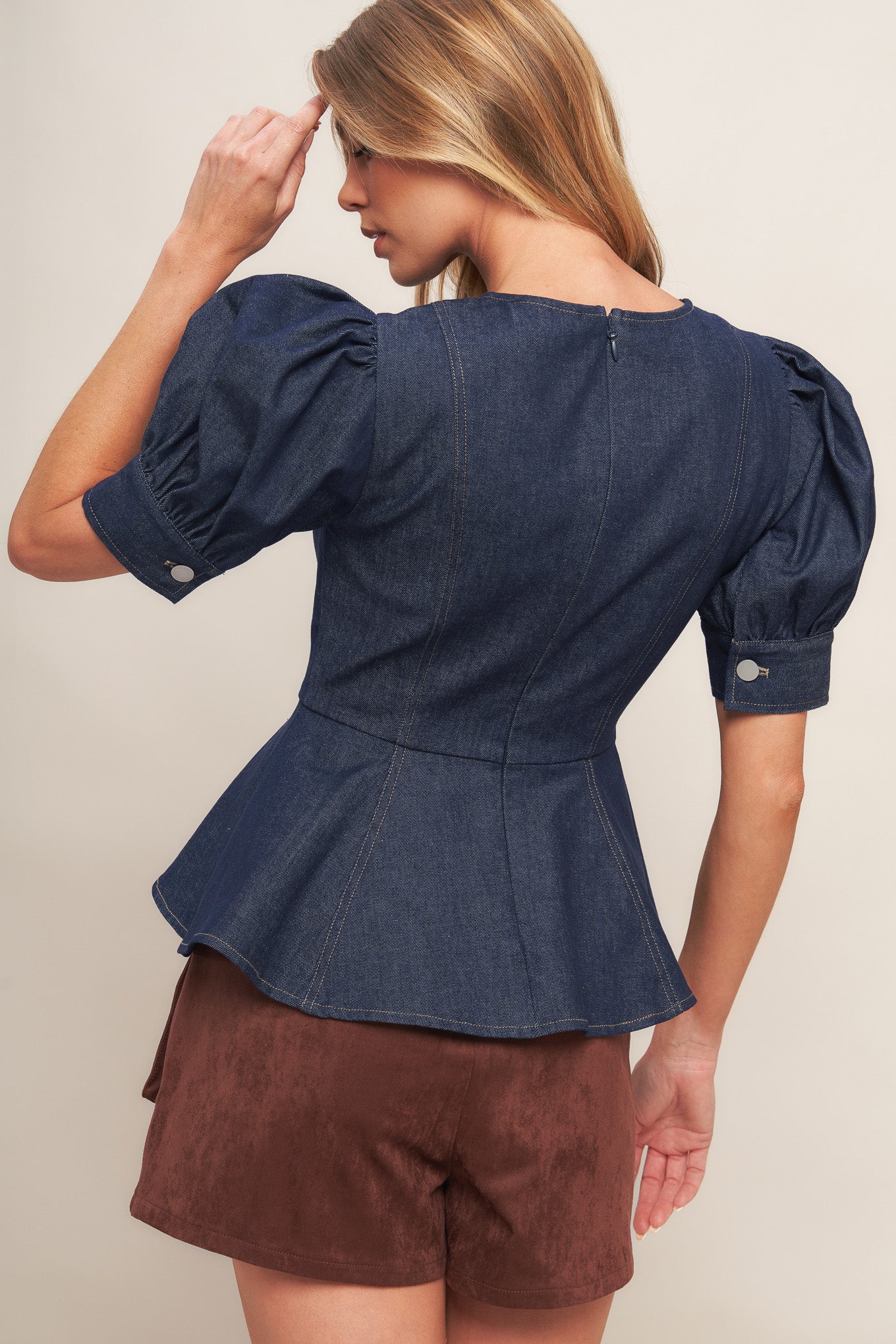 A denim top featuring round neckline, short puff sleeve with cuff, peplum and back zipper closure