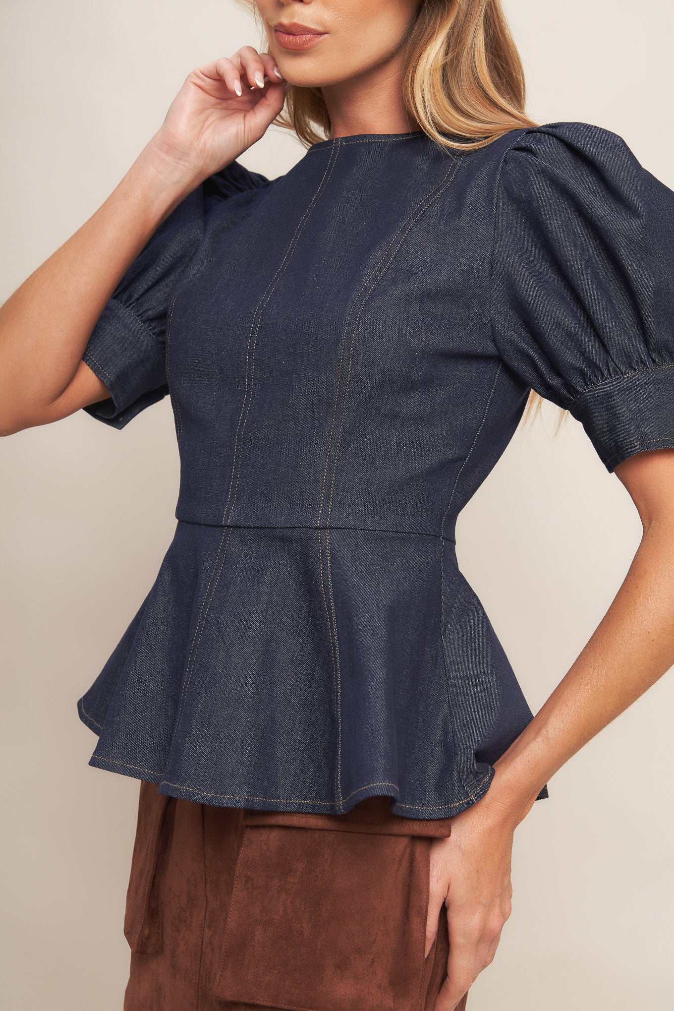 A denim top featuring round neckline, short puff sleeve with cuff, peplum and back zipper closure
