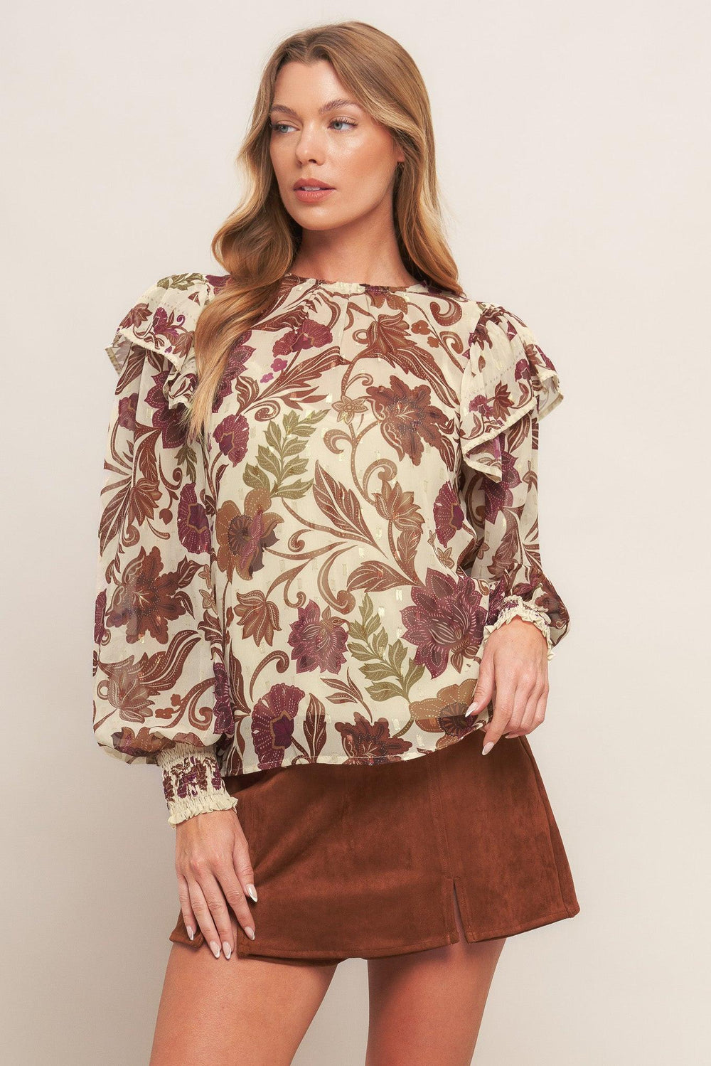 A printed woven top featuring round neckline, long sleeve with cuff and ruffled shoulder and back neck button closure