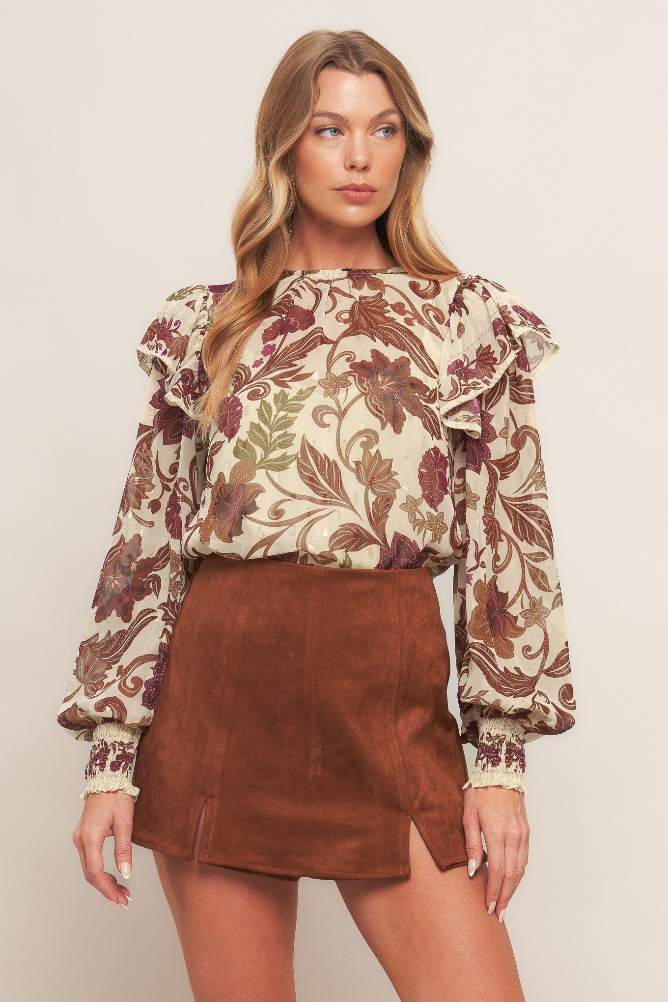 A printed woven top featuring round neckline, long sleeve with cuff and ruffled shoulder and back neck button closure