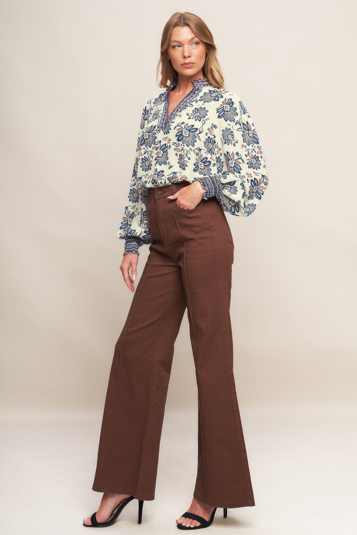 A printed woven top featuring ruffled neckline with V front and long sleeve with smocked cuff