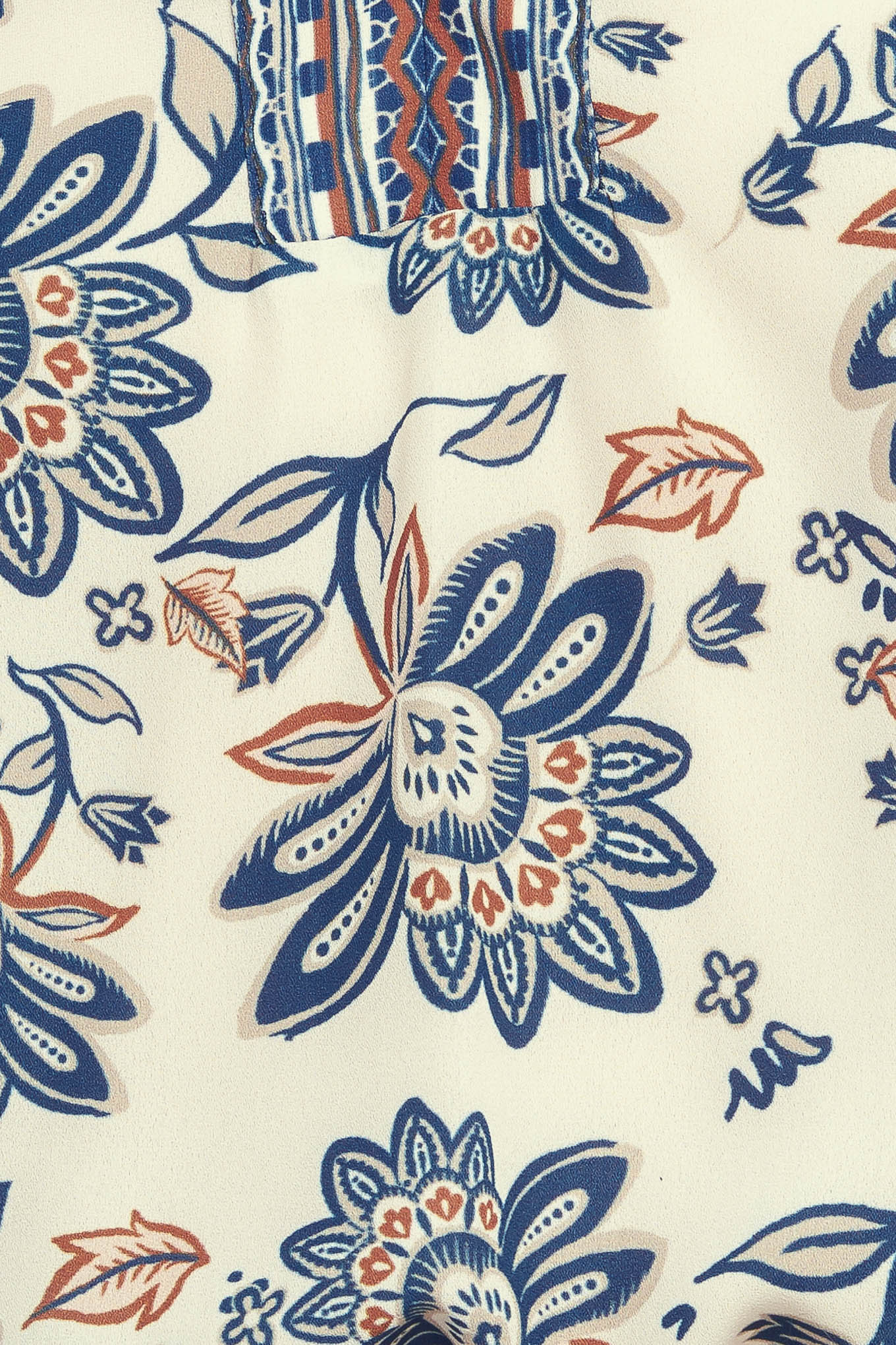 A printed woven top featuring ruffled neckline with V front and long sleeve with smocked cuff