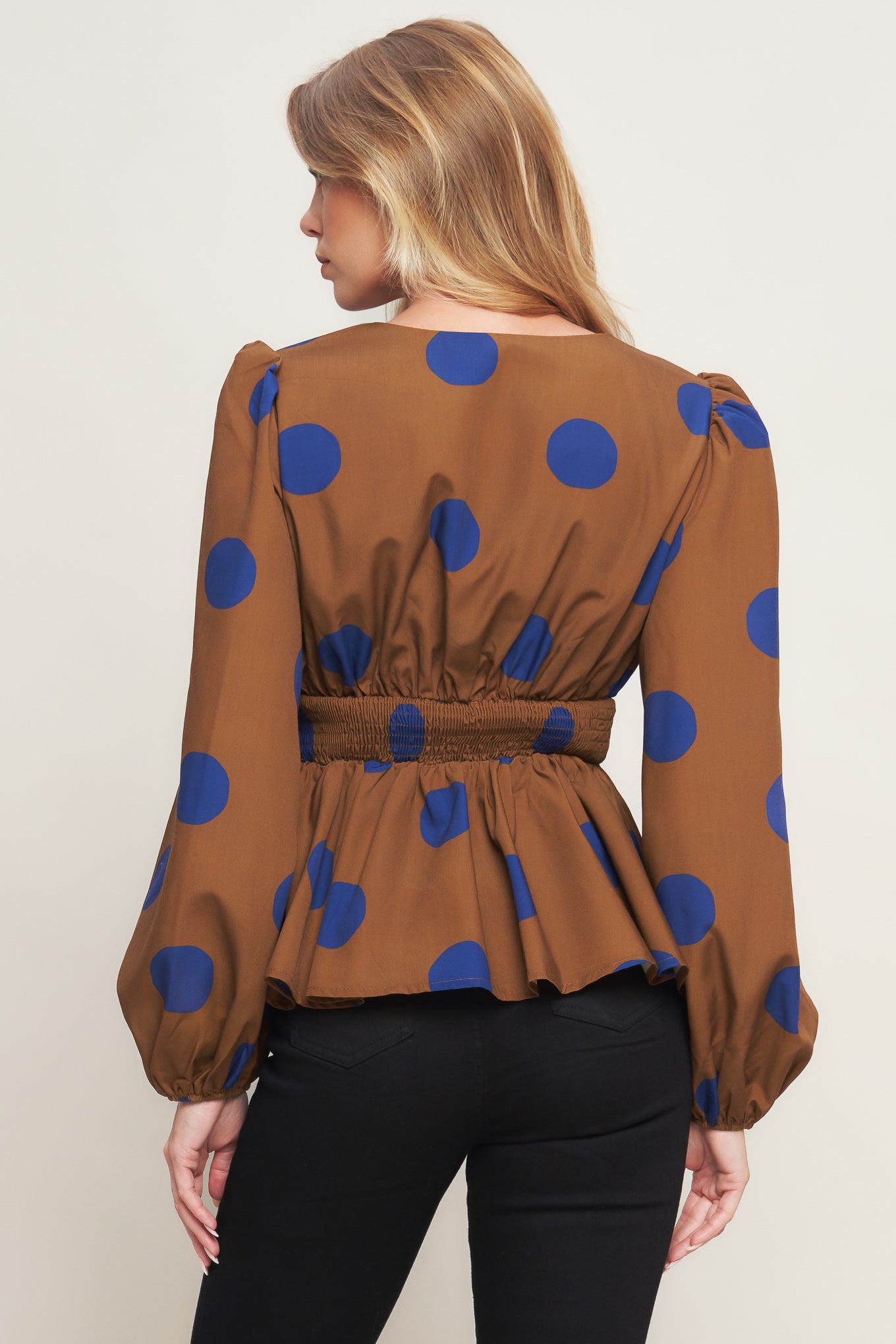 A printed woven top featuring V neckline, long sleeve, waist yoke, peplum and smocked back waist band