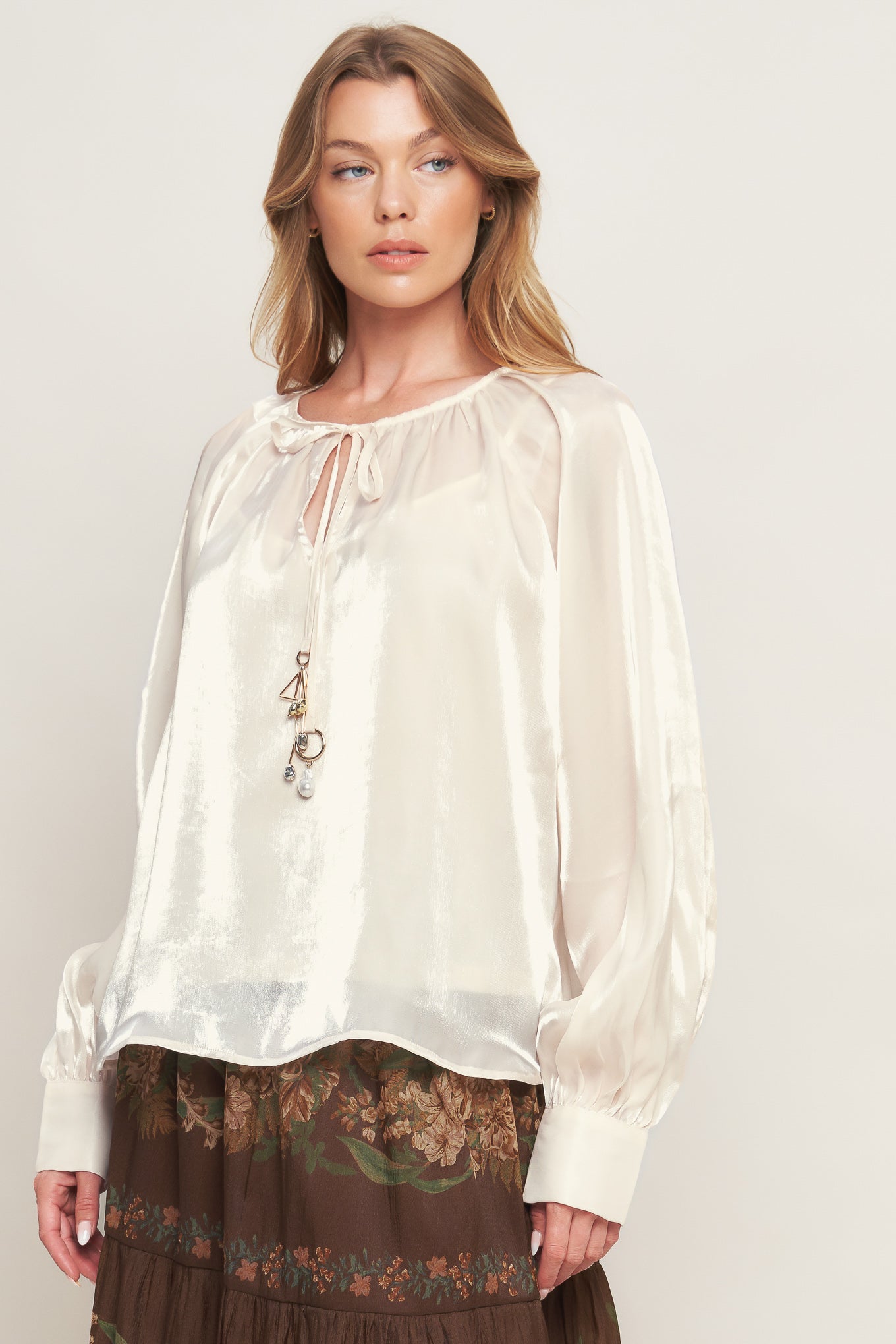 A solid sheen woven peasant top with front tie with embellishment, long sleeve with cuff and cami