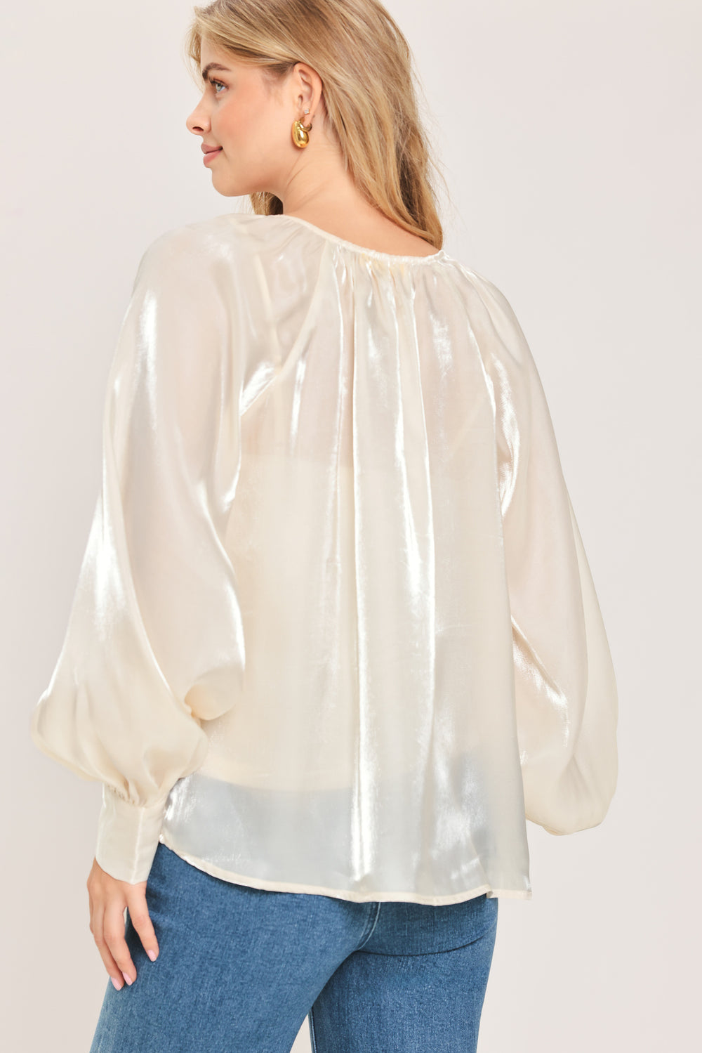 Woman wearing an ivory champagne long sleeve blouse with a front tie and charms | Flying Tomato