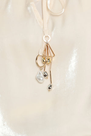 Woman wearing an ivory champagne long sleeve blouse with a front tie and charms | Flying Tomato