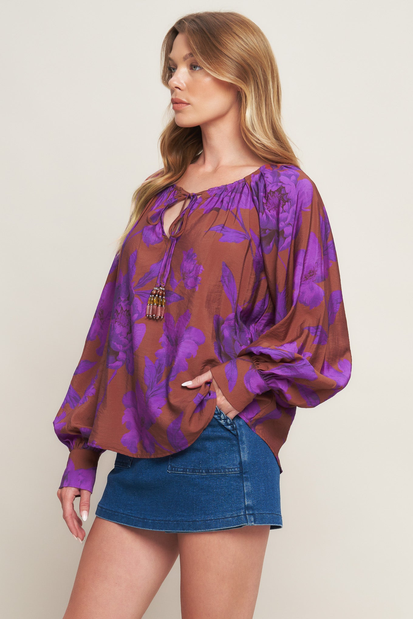 A printed woven peasant top featuring round neckline with tie and long sleeve with cuff