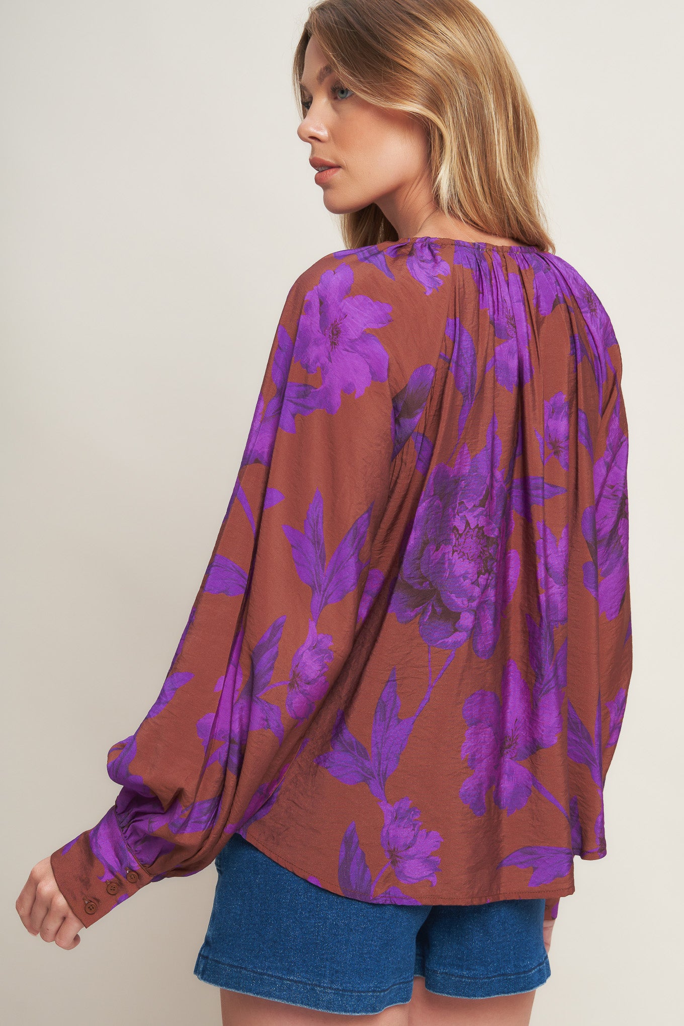 A printed woven peasant top featuring round neckline with tie and long sleeve with cuff