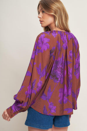 A printed woven peasant top featuring round neckline with tie and long sleeve with cuff