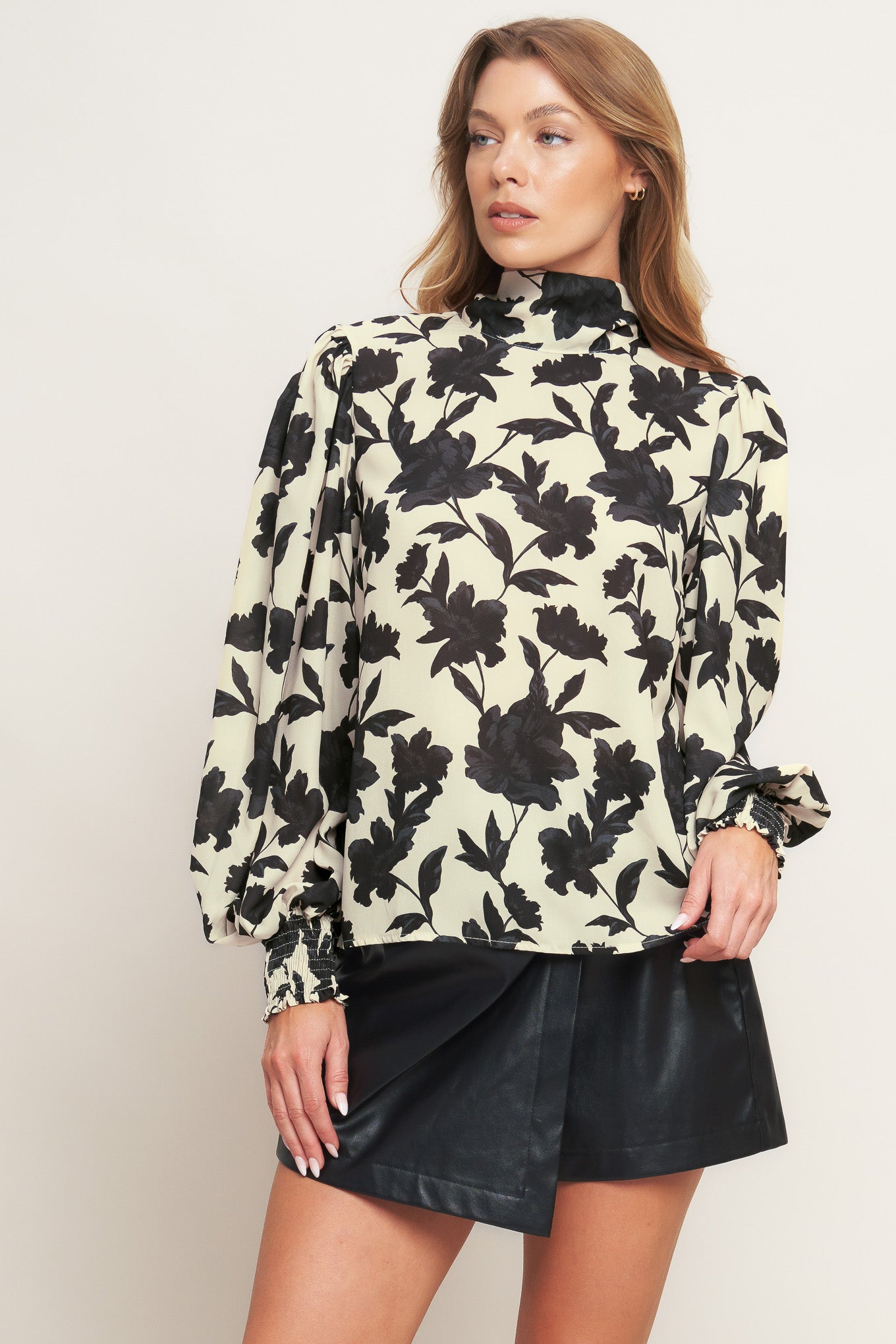 A printed woven top featuring high neckline, long sleeve and back bow tie closure