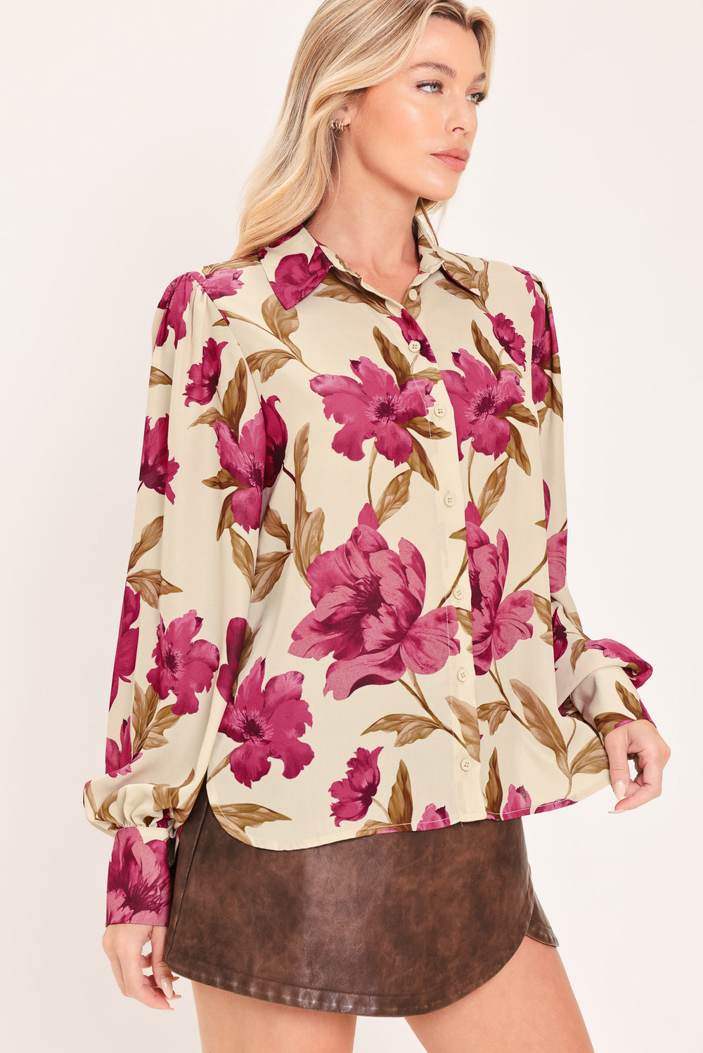 A woman modeling a cream-colored long-sleeve button-up blouse with a bold magenta and brown floral print | Flying Tomato