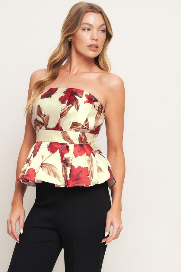 A printed woven top featuring strapless neckline, pleated body, peplum and smocked back bodice. 