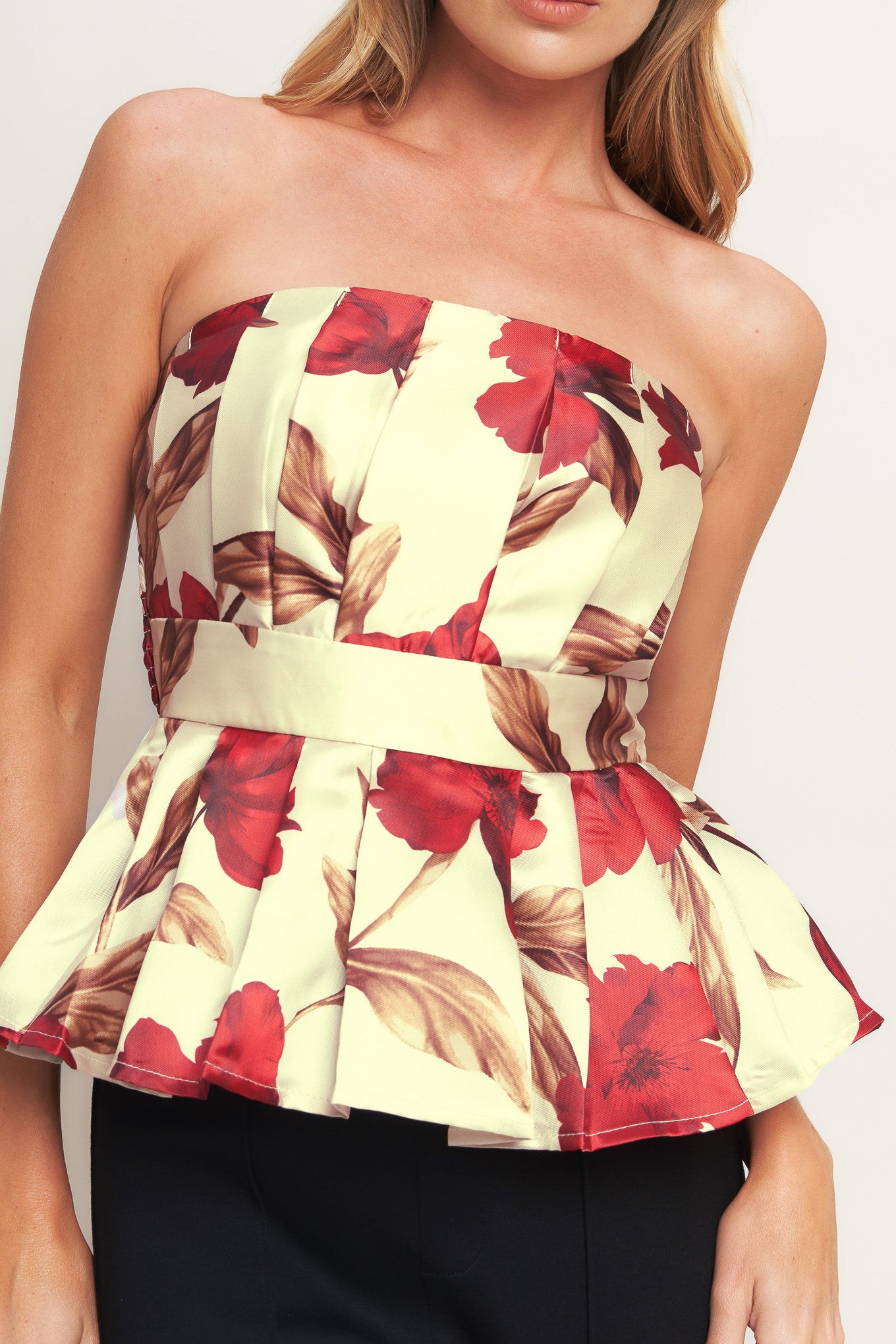 A printed woven top featuring strapless neckline, pleated body, peplum and smocked back bodice. 