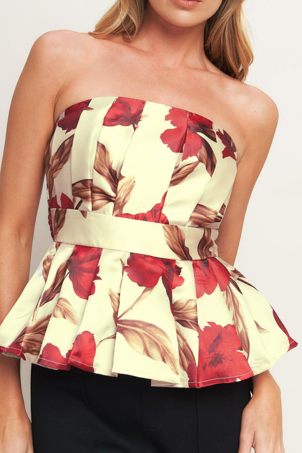 A printed woven top featuring strapless neckline, pleated body, peplum and smocked back bodice. 