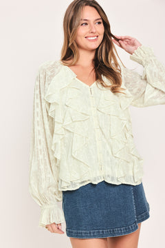 Woman wearing a cream long sleeve blouse with ruffles running down the torso | Flying Tomato