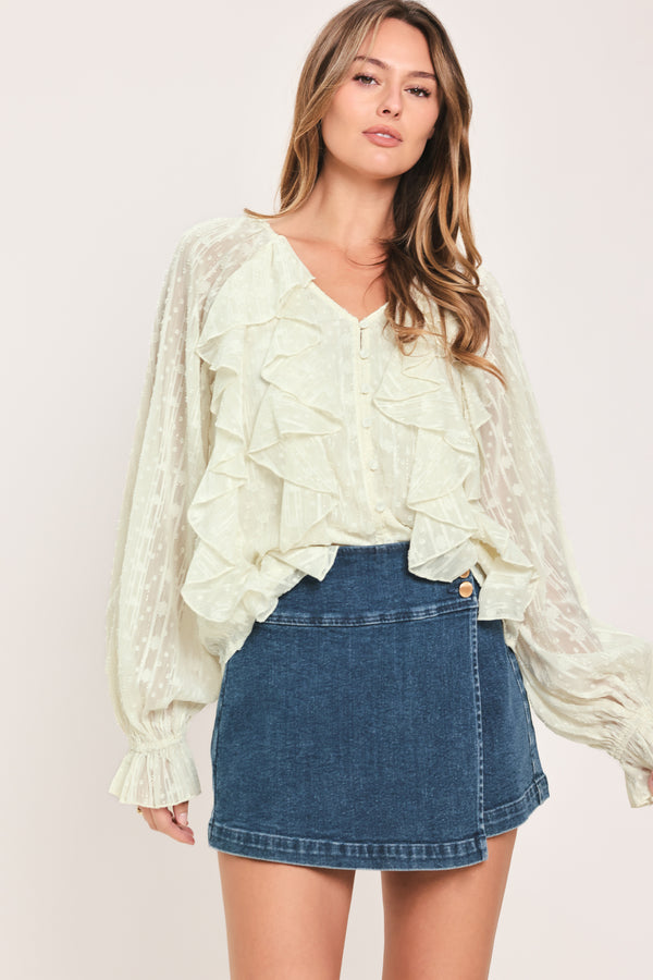 Woman wearing a cream long sleeve blouse with ruffles running down the torso | Flying Tomato
