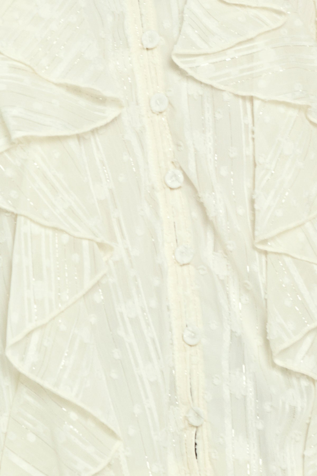 Woman wearing a cream long sleeve blouse with ruffles running down the torso | Flying Tomato