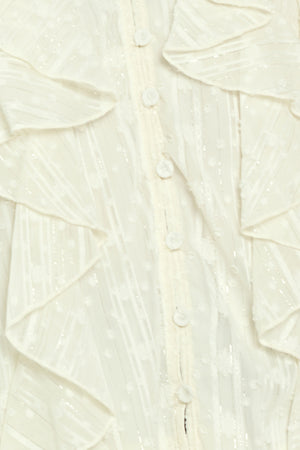 Woman wearing a cream long sleeve blouse with ruffles running down the torso | Flying Tomato