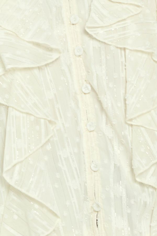 Woman wearing a cream long sleeve blouse with ruffles running down the torso | Flying Tomato