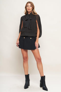 A woven dotted top featuring front bow tie and capelet.