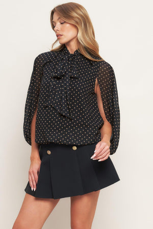 A woven dotted top featuring front bow tie and capelet.